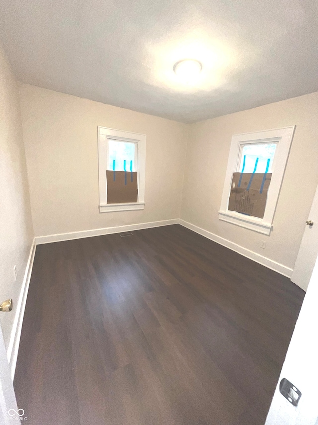 unfurnished room with dark wood-type flooring and a textured ceiling