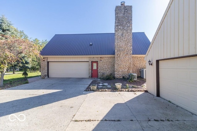 1205 Ivywood Ct, New Castle, IN 47362 - view of front of house featuring a garage, central AC, a chimney, board and batten siding, and metal roof