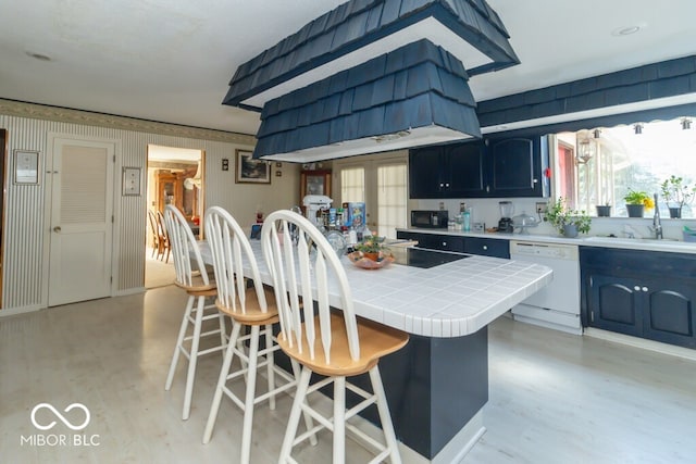 kitchen featuring a breakfast bar area, tile countertops, sink, and black appliances