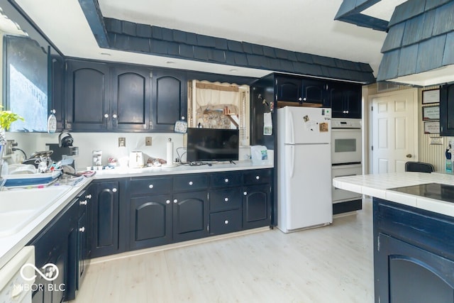 kitchen with light wood-type flooring, sink, and white appliances