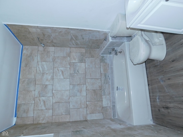 bathroom with tiled shower, toilet, and tile patterned floors