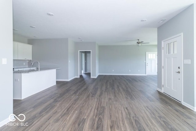 unfurnished living room featuring ceiling fan, sink, and dark wood-type flooring