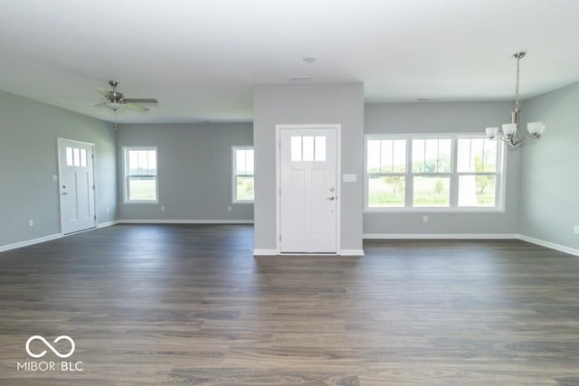 unfurnished living room with ceiling fan with notable chandelier and dark wood-type flooring