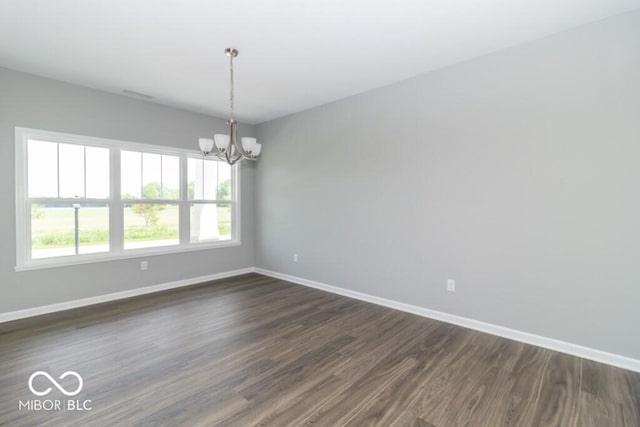 unfurnished room featuring dark wood-type flooring and a notable chandelier