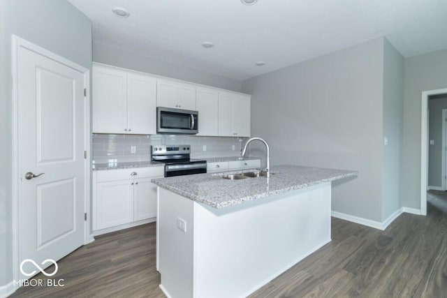 kitchen with tasteful backsplash, stainless steel appliances, sink, white cabinets, and an island with sink