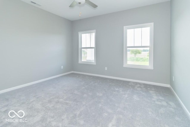 carpeted spare room featuring ceiling fan and a healthy amount of sunlight