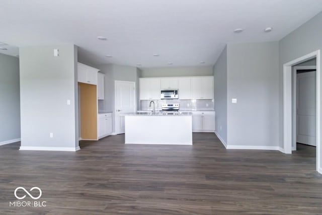 kitchen with tasteful backsplash, white cabinetry, an island with sink, and dark wood-type flooring