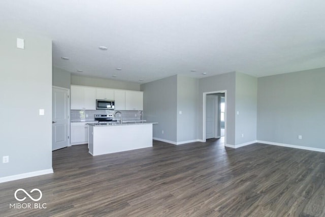 kitchen featuring backsplash, a center island with sink, appliances with stainless steel finishes, dark hardwood / wood-style flooring, and white cabinetry