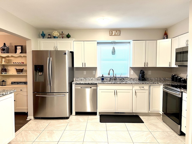 kitchen with white cabinets, appliances with stainless steel finishes, a sink, and light stone counters