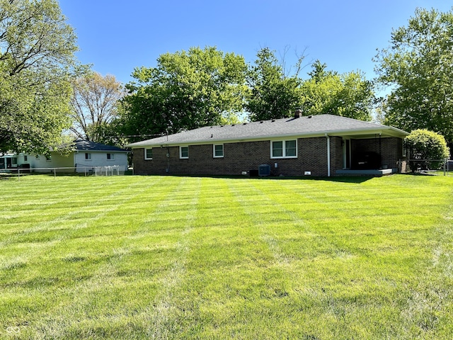 back of property featuring a yard, brick siding, and fence