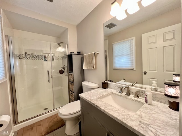 bathroom with visible vents, a stall shower, toilet, and vanity