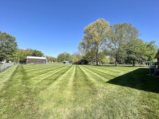 view of yard featuring central AC and fence
