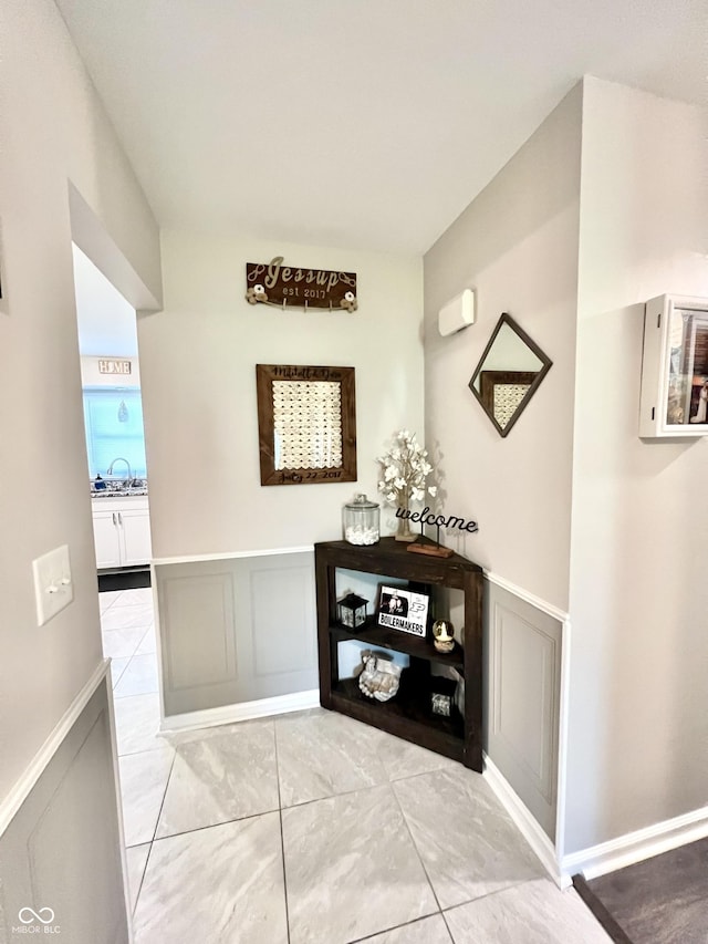 hallway with a sink, a wainscoted wall, and a decorative wall