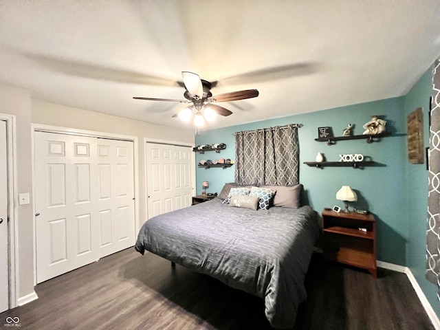 bedroom with two closets, baseboards, ceiling fan, and wood finished floors