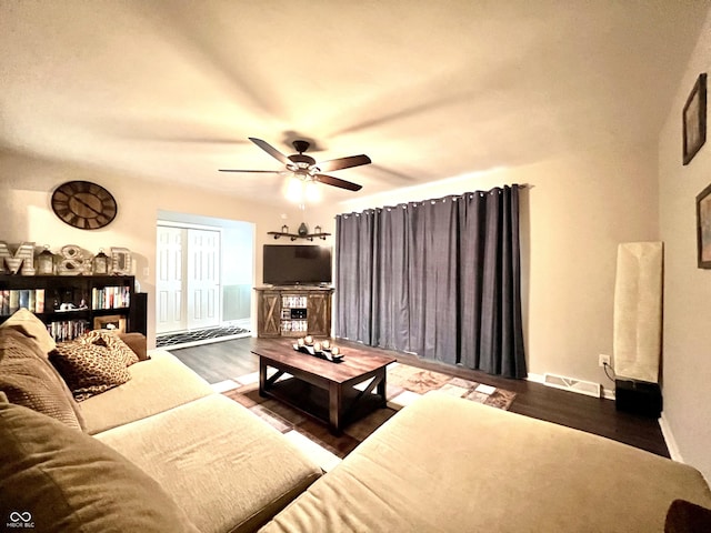 living area featuring ceiling fan, visible vents, baseboards, and wood finished floors