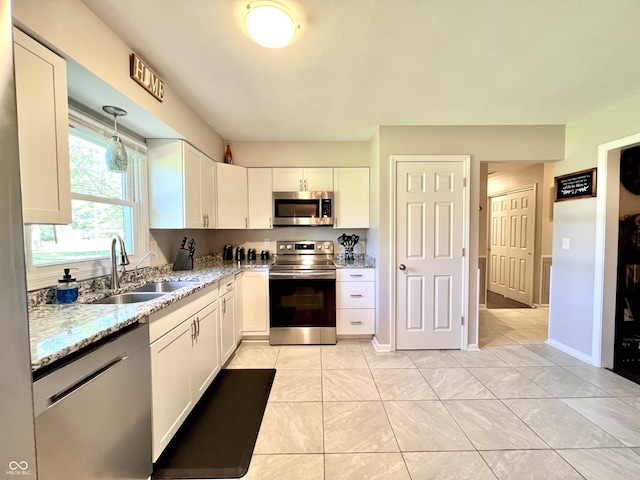 kitchen with a sink, light stone counters, stainless steel appliances, and white cabinetry