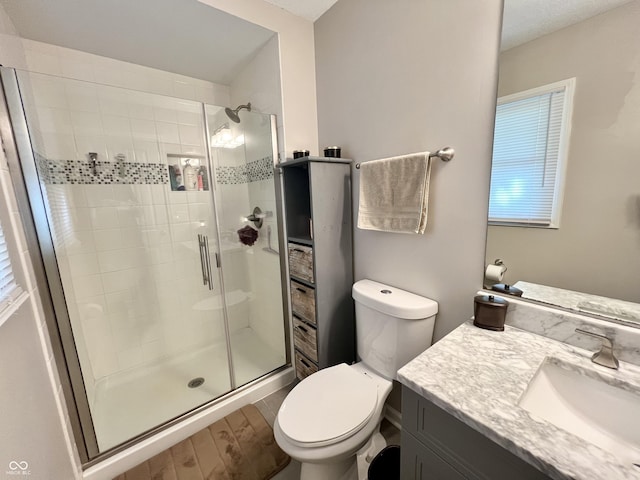 bathroom with toilet, a stall shower, wood finished floors, and vanity