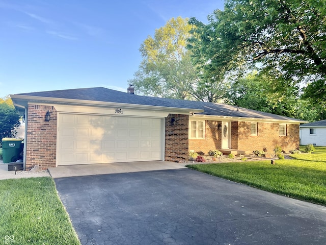 ranch-style house with a garage, a front lawn, a chimney, brick siding, and driveway