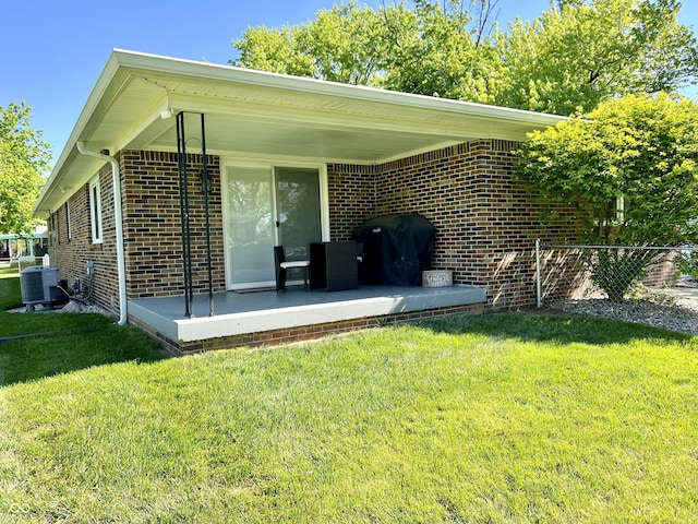 rear view of property with a yard, brick siding, and cooling unit