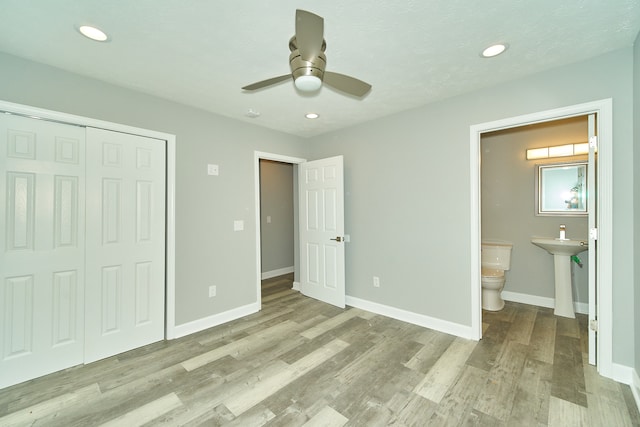 unfurnished bedroom with light hardwood / wood-style floors, connected bathroom, a closet, and ceiling fan