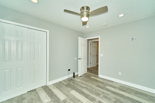 unfurnished bedroom featuring ceiling fan, light hardwood / wood-style floors, and a closet