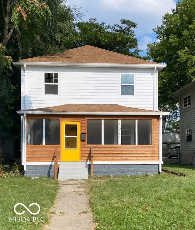 view of front of home with a sunroom and a front lawn