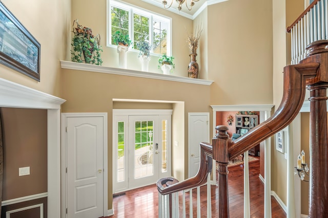 entryway with a notable chandelier, hardwood / wood-style flooring, and crown molding