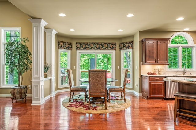 dining area with a healthy amount of sunlight, dark wood-type flooring, and ornate columns