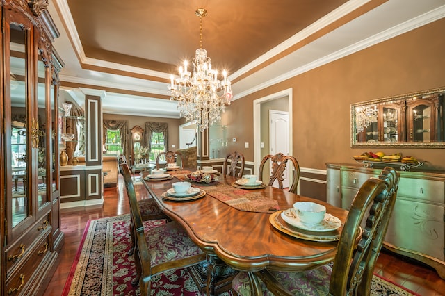 dining room with a tray ceiling, ornamental molding, dark hardwood / wood-style flooring, and an inviting chandelier