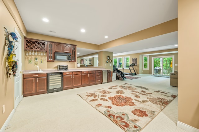 kitchen featuring wine cooler, sink, and light carpet