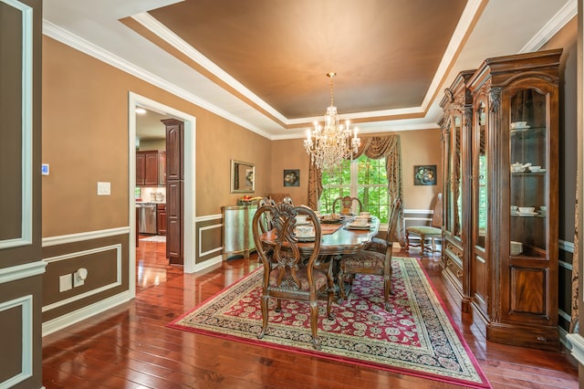 dining room with an inviting chandelier, crown molding, dark hardwood / wood-style floors, and a raised ceiling