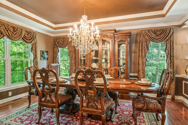 dining room featuring crown molding, dark hardwood / wood-style floors, an inviting chandelier, and a raised ceiling