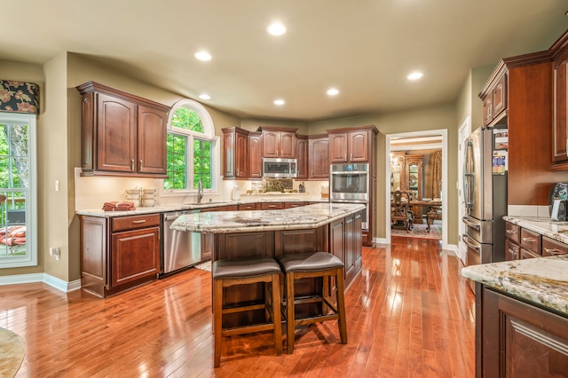 kitchen featuring a healthy amount of sunlight, a center island, stainless steel appliances, and wood-type flooring