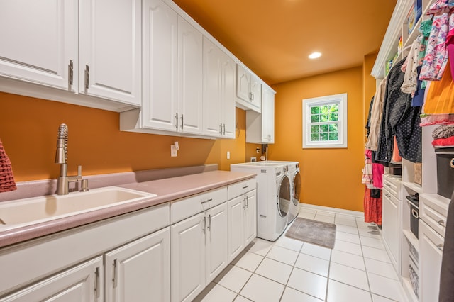 clothes washing area with washing machine and dryer, light tile floors, cabinets, and sink