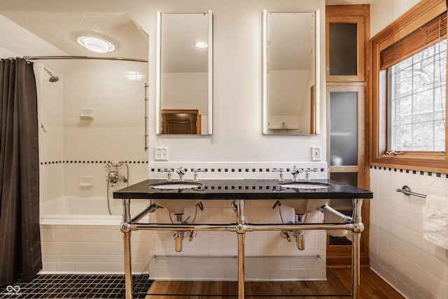 bathroom featuring shower / bath combo, dual sinks, wood-type flooring, and tile walls