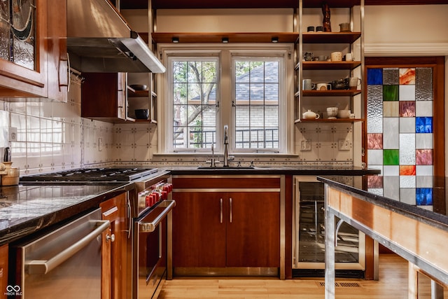 kitchen with tasteful backsplash, stainless steel appliances, sink, dark stone countertops, and range hood