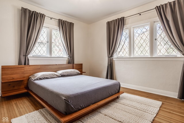 bedroom with multiple windows and hardwood / wood-style flooring