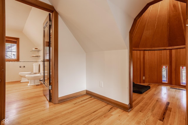 additional living space featuring lofted ceiling and light wood-type flooring