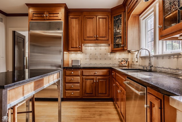 kitchen with sink, light hardwood / wood-style flooring, ornamental molding, tasteful backsplash, and stainless steel appliances