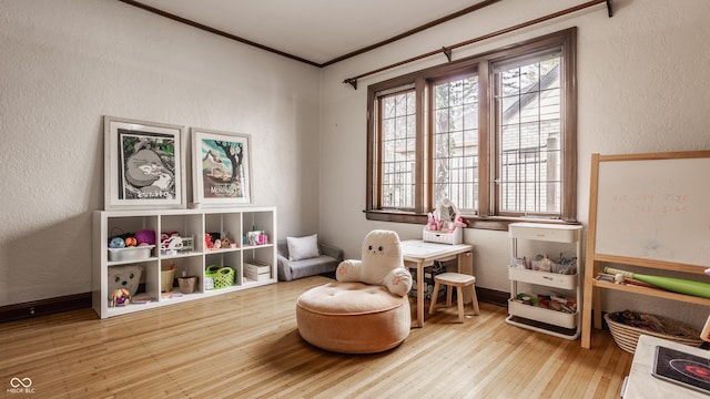 rec room featuring light wood-type flooring and ornamental molding