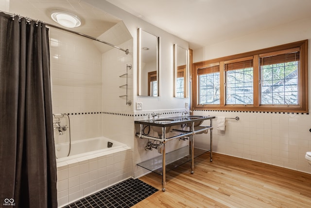 bathroom featuring shower / bath combo with shower curtain, wood-type flooring, and tile walls