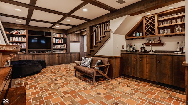 bar with built in shelves, wood walls, dark brown cabinetry, and coffered ceiling