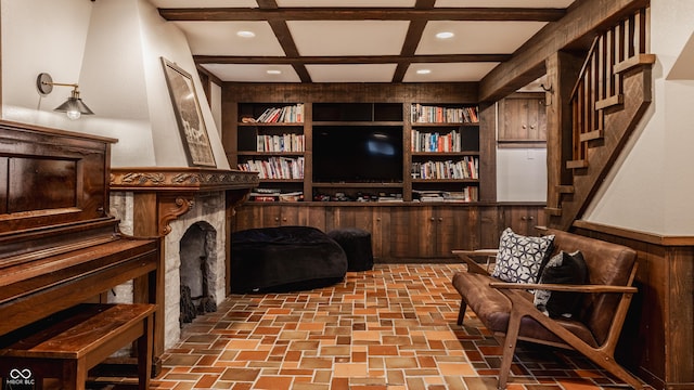 sitting room featuring beamed ceiling, built in features, coffered ceiling, and wood walls