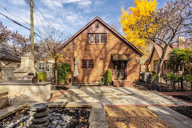 tudor home with a fireplace, area for grilling, and a patio area