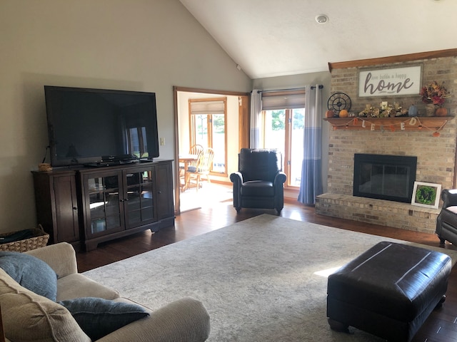 living room featuring a fireplace, brick wall, dark hardwood / wood-style floors, and high vaulted ceiling