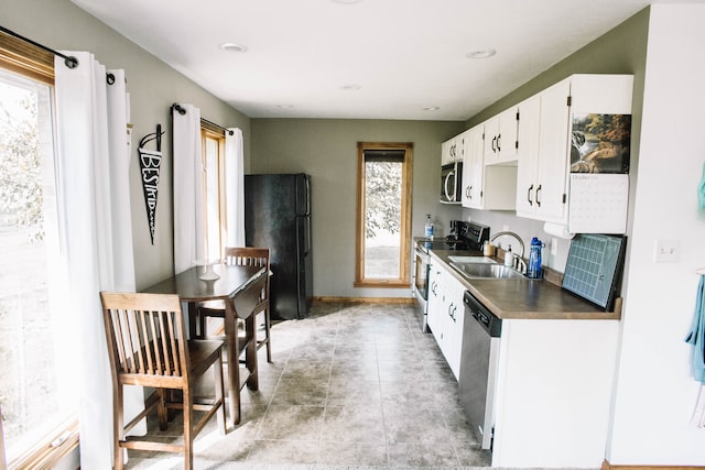 kitchen featuring appliances with stainless steel finishes, sink, a wealth of natural light, and white cabinetry