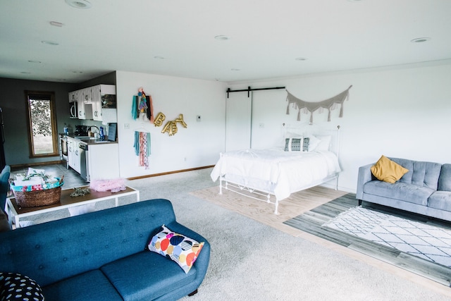 bedroom featuring a barn door, sink, and light carpet