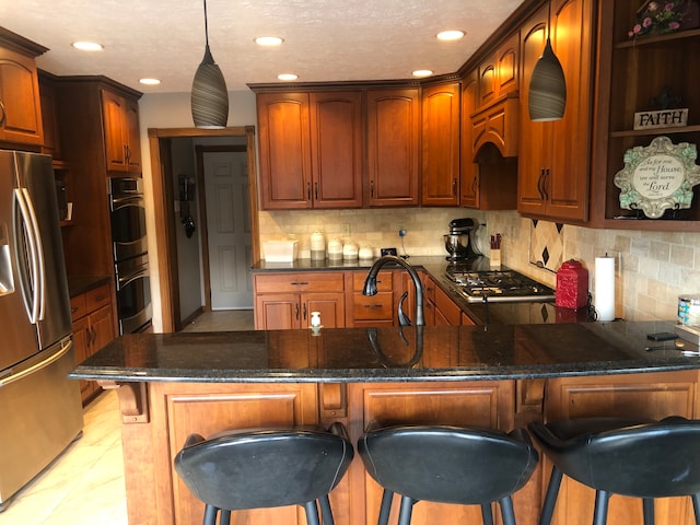 kitchen featuring stainless steel fridge, a breakfast bar area, hanging light fixtures, and tasteful backsplash