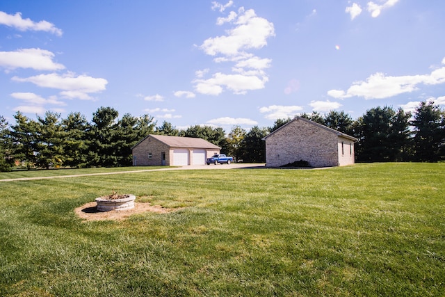 view of yard featuring an outdoor fire pit and a garage