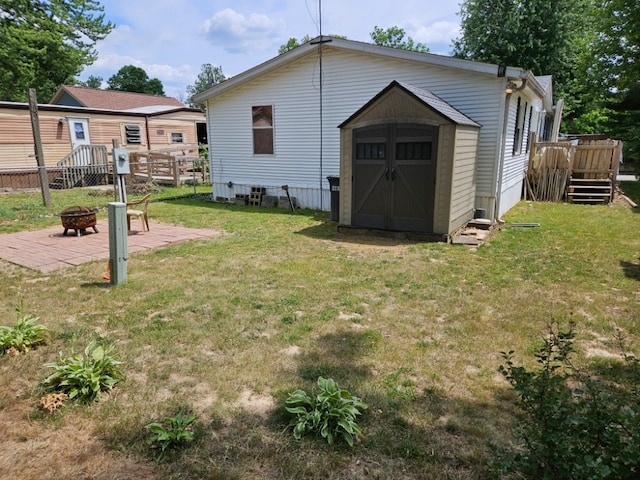 rear view of house featuring a storage unit, a lawn, an outdoor fire pit, and a wooden deck